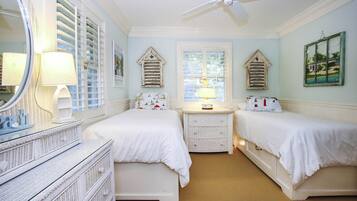 A bedroom with two beds, a dresser, a mirror, a ceiling fan, and a window with shutters.
