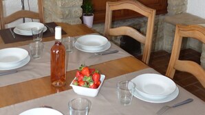 A dining table set with plates, cutlery, and a bottle of water, with a stone wall and wooden beams in the background. - Provence - Detached house with private pool (Aubignan)