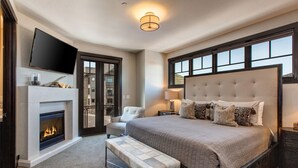 A bedroom with a large bed, a flat-screen TV, a fireplace, and a bench. - Luxe Townhome in Prime Location, Private Hot Tub, Chef (Park City)