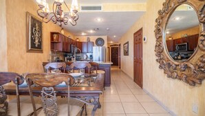 Un'ampia cucina con mobili in legno, una zona pranzo con un tavolo e sedie grandi e uno specchio decorativo appeso al muro.