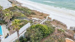 Une propriété située en bord de mer, dotée d’une piscine, d’une terrasse en bois et offrant une vue sur l’océan.