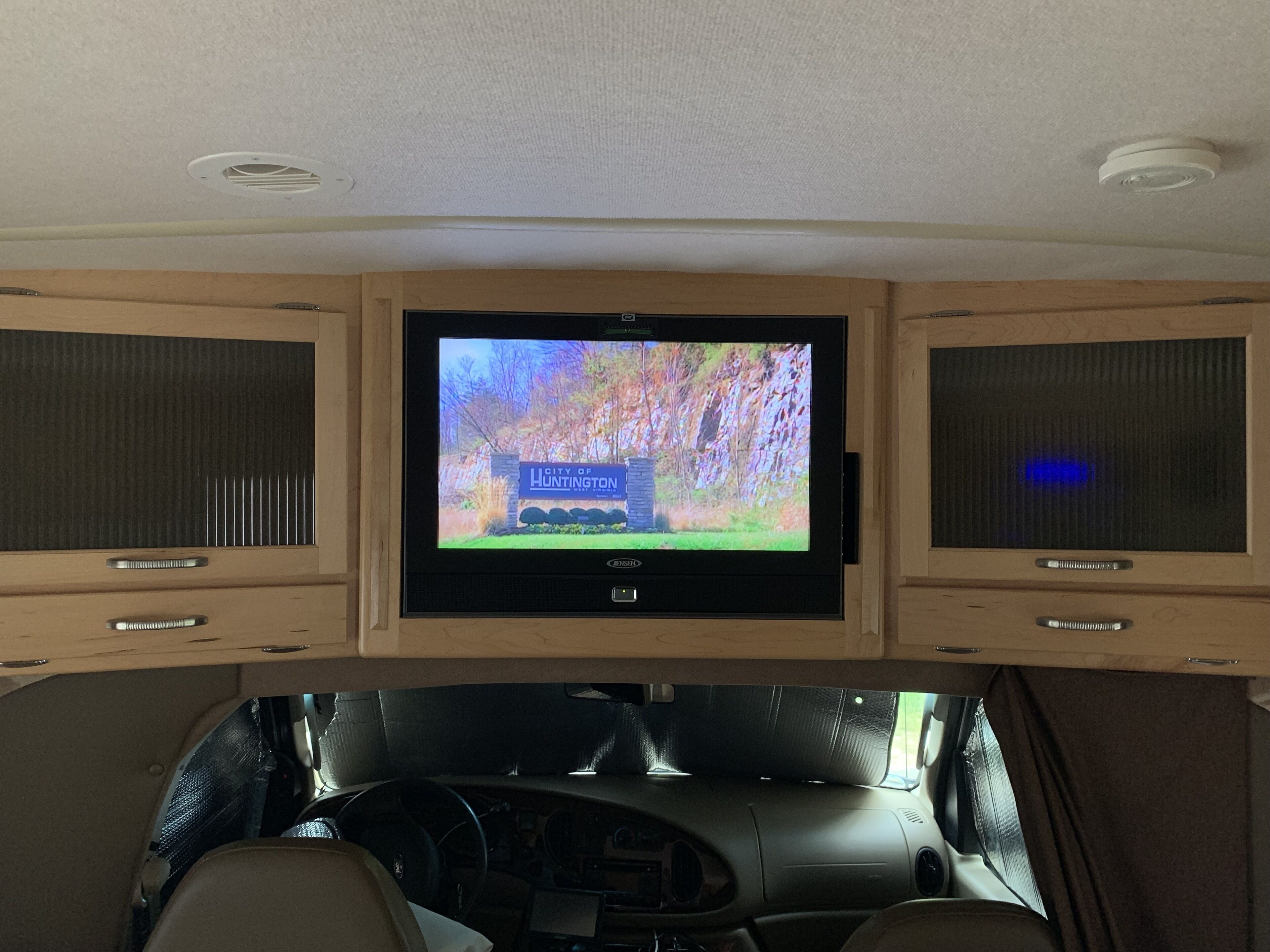A vehicle interior with a mounted television displaying a city sign.