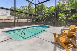Piscina interior com deck de madeira, escada de piscina e vista para vegetação exuberante.