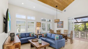 Ein geräumiges Wohnzimmer mit einem blauen Sofa, einem Holztisch und einem Essbereich mit Tisch und Stühlen.
