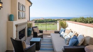 Un balcon avec un canapé, des chaises, une table et une cheminée.