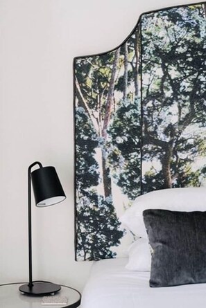 A bedroom with a bed, a black floor lamp, and a wall with a forest print. - The Florance (Launceston)