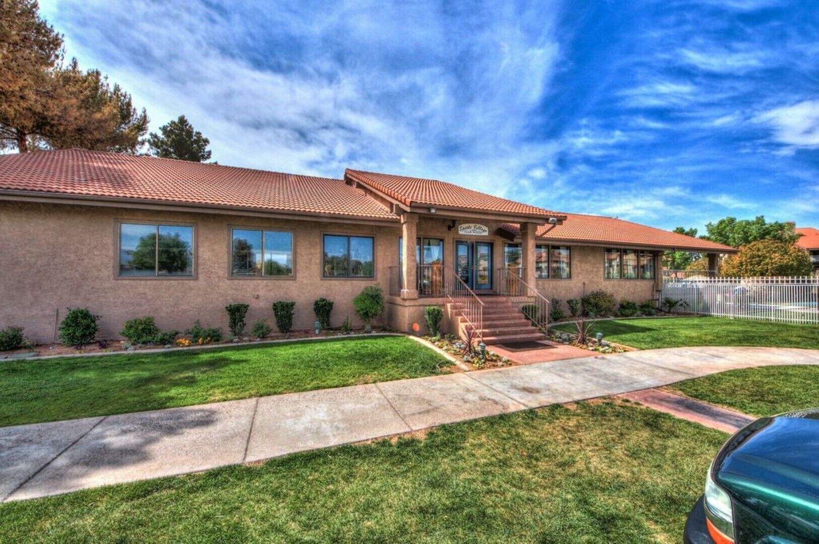A two-story building with a red-tiled roof, a front porch, and a well-maintained lawn.