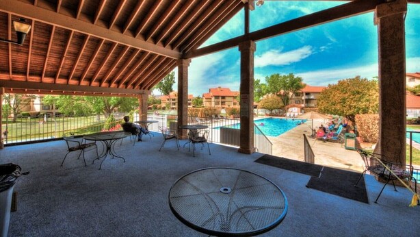 Un patio al aire libre con mesas y sillas, piscina y vistas del vecindario.