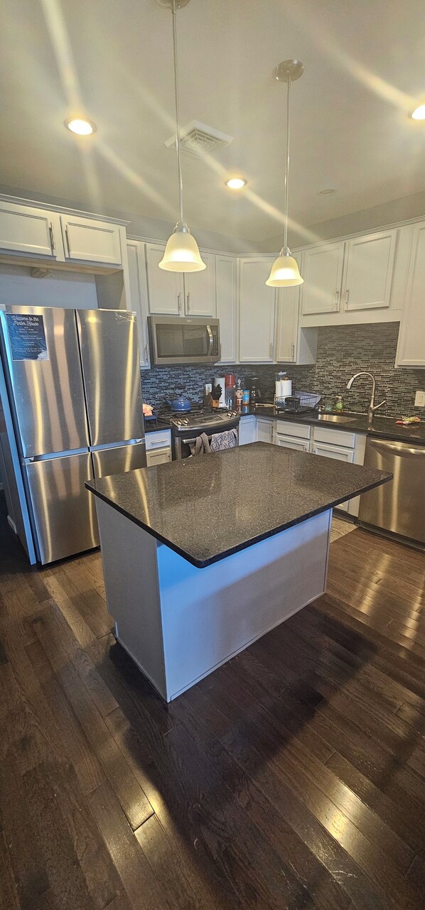 A modern kitchen with a central island, stainless steel appliances, and pendant lighting.