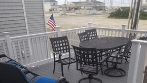 A covered outdoor seating area with a table and chairs, a blue lounge chair, and a white railing. - Pet friendly- 1/2 block from beach Seaside Heights/Seaside park - ocean views.  (Seaside Heights)