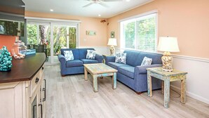 A living room with a blue sofa set, two coffee tables, and a ceiling fan.