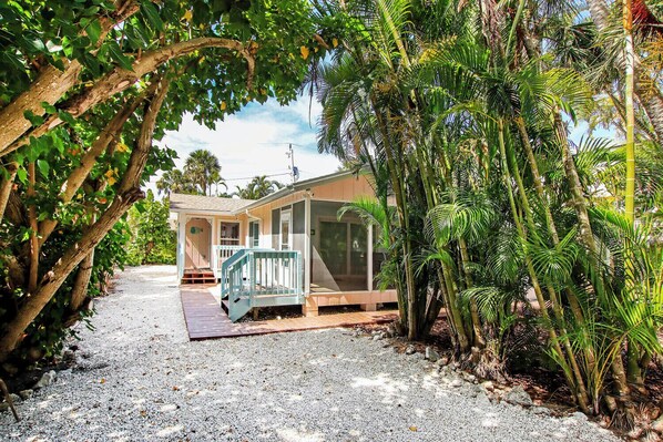 A house with a porch, surrounded by tropical vegetation.