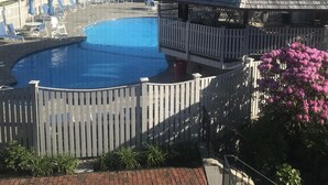 A swimming pool with lounge chairs and a wooden fence, surrounded by a brick pathway and greenery. - Townhouse-Beach Vacation at the Yachtsman in Hyannis (Barnstable)