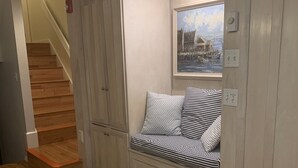 A room with a built-in bench against a wall, a round granite table in the foreground, and a staircase leading to another level. - Townhouse-Beach Vacation at the Yachtsman in Hyannis (Barnstable)