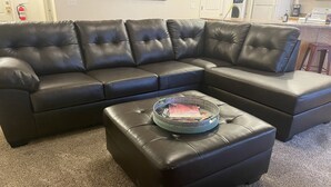 Un canapé modulable et un pouf dans un salon dont le sol est recouvert d’une moquette.