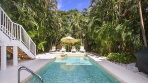 A pool with clear water, surrounded by lush greenery and a white staircase. - Spacious 5BR Captiva Retreat with Private Pool, Spa & Game Room (Captiva)
