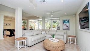 A modern living room with a sectional sofa, two round coffee tables, and a large window with a view of the outdoors. - Spacious 5BR Captiva Retreat with Private Pool, Spa & Game Room (Captiva)