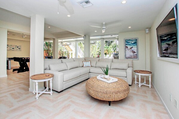 A modern living room with a sectional sofa, two round coffee tables, and a large window with a view of the outdoors.
