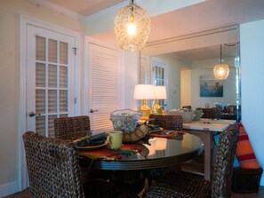 A dining area with a round table, chairs, a lamp, and a mirror. - Family friendly with a great ocean view (Pensacola Beach)