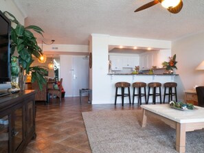 A spacious living area with a kitchen, a dining table, and a TV.
