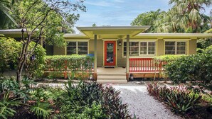 A house with a red door, yellow siding, and a porch with a red railing. - Colorful 4BR Captiva Village Retreat with Private Heated Pool (Captiva)