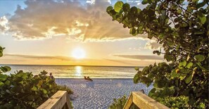 A wooden pathway leading to a beach with a sunset in the background. - 707 Palms Resort | Private Pool & Huge Fenced Yard (Naples)