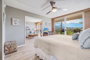 Ein geräumiges Schlafzimmer mit einem großen Bett, einem Deckenventilator und Blick ins Freie.