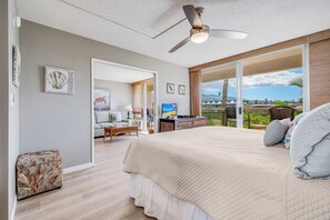 A spacious bedroom with a large bed, a ceiling fan, and a view of the outdoors.