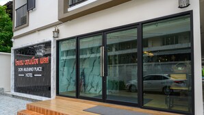 A hotel entrance with a marble facade, large glass doors, and a wooden staircase leading up to the entrance. - Donmueang Place Hotel (Bangkok)