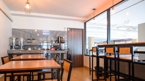 A modern kitchen with marble backsplash, wooden tables, and bar stools. - Donmueang Place Hotel (Bangkok)
