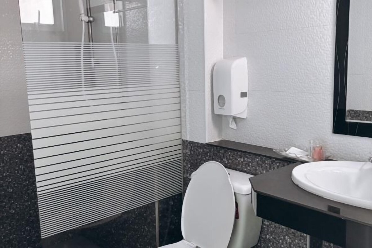 A modern bathroom with a toilet, a sink, and a hand soap dispenser.