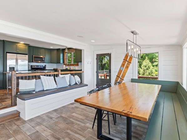 Una cocina moderna con armarios verde oscuro, electrodomésticos de acero inoxidable y un banco de madera con cojines.