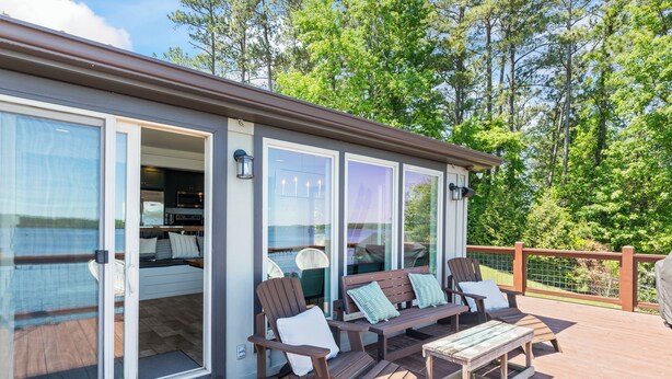 A deck with wooden furniture, including chairs and a table, and a sliding glass door leading to a kitchen area.