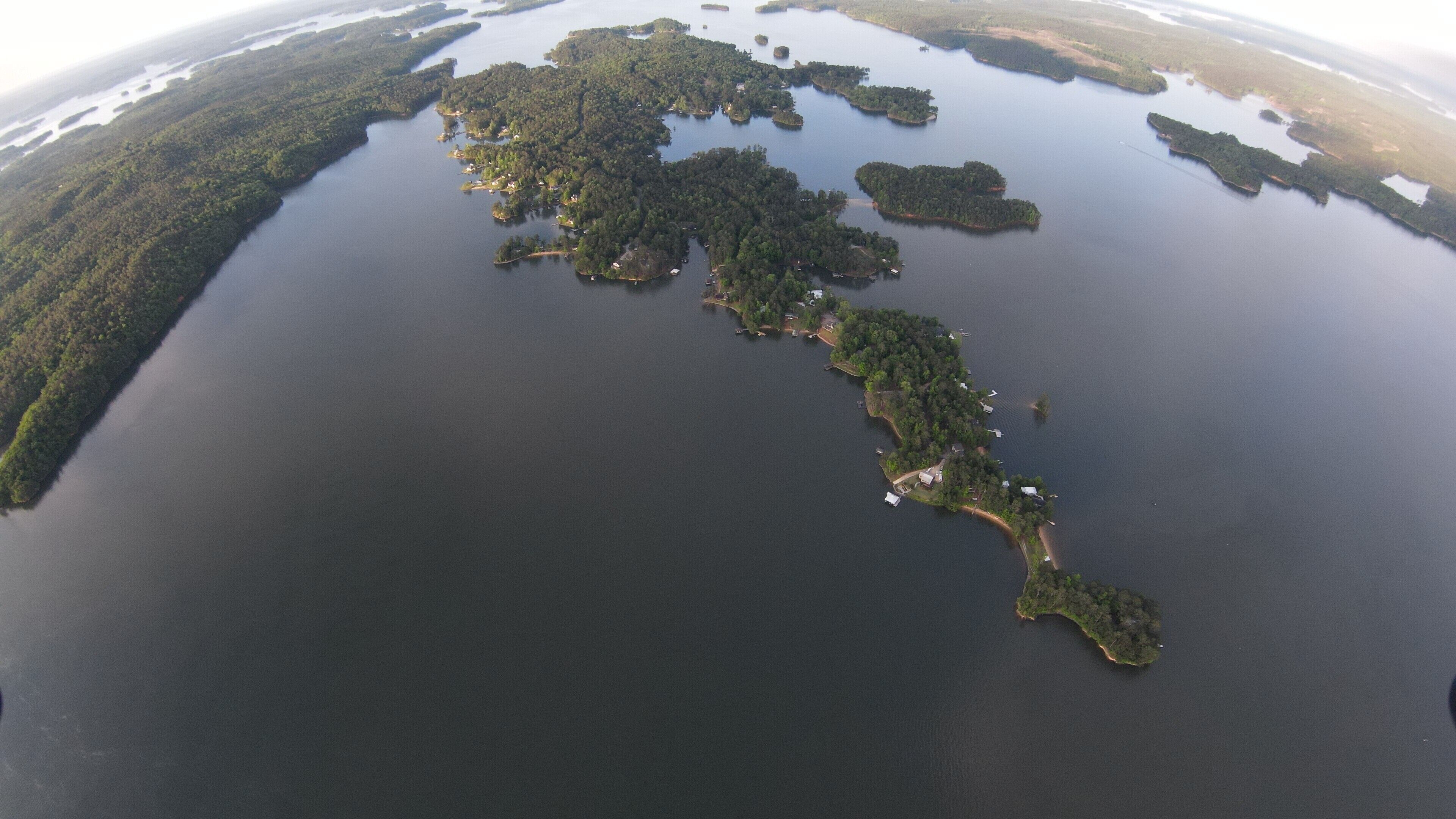 Luchtbeeld van een groot waterlichaam met verschillende eilanden, elk omringd door dicht bos.