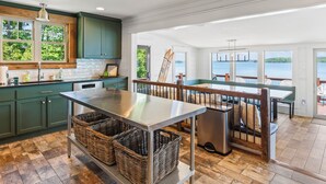 A modern kitchen with a large island, wooden flooring, and a view of the lake.
