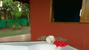 Eine weiße Badewanne mit Abfluss, ein grüner Zaun und ein Fenster im Hintergrund.