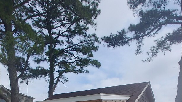 A house with a covered porch, a red grill, and two potted plants. - Island Time Cottage (Chincoteague)