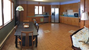 A kitchen with a dining table, chairs, a refrigerator, and a microwave. - Year round lakefront house on Keuka Lake (Hammondsport)