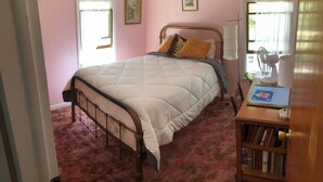 A bedroom with a bed, a bedside table with a lamp, a window, and a door. - Year round lakefront house on Keuka Lake (Hammondsport)