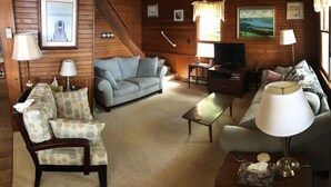 A cozy cabin-style room with a sofa, armchairs, a coffee table, and a television. - Year round lakefront house on Keuka Lake (Hammondsport)