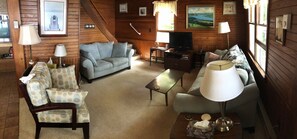 Cozy cabin interior with a comfortable seating area, flat-screen TV, and dining table.