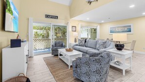 A living room with a sofa, armchairs, a coffee table, a cabinet, and a ceiling-mounted fish decoration.