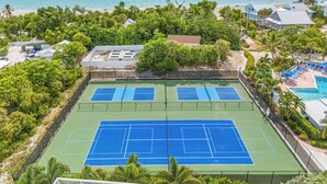 A tennis court with a pool and a beach view.