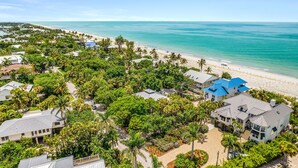 An aerial view of a coastal residential area with houses, a beach, and a clear blue sky.