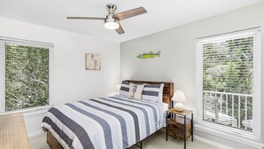 A bedroom with a bed, a nightstand, a ceiling fan, and a window with blinds. - Modern 2-Bedroom Retreat Steps from Captiva Beach (Captiva)