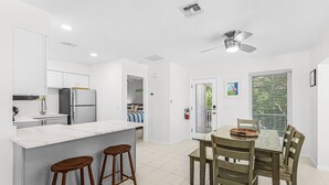 A modern kitchen with a central island, bar stools, and a dining table with chairs.