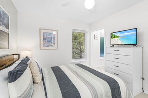 Un dormitorio con cama, televisión, cómoda y ventana con persianas.