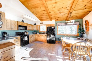 Enjoy meals in this kitchen with a dining table and chairs, a large refrigerator, and a window.