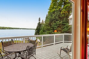 Enjoy a serene lakeside view from this outdoor deck, featuring a round table and comfortable seating for four, plus a cozy rocking chair.