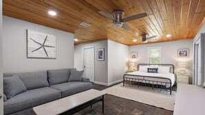 A bedroom with a bed, a bench, a sofa, and a ceiling fan. - Charming Island Escape with Private Pool and Screened Lanai! (Anna Maria)